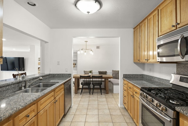 2171 Martinique Ln, Oxnard, CA 93035 - kitchen featuring appliances with stainless steel finishes, dark stone counters, light tile patterned flooring, and a chandelier