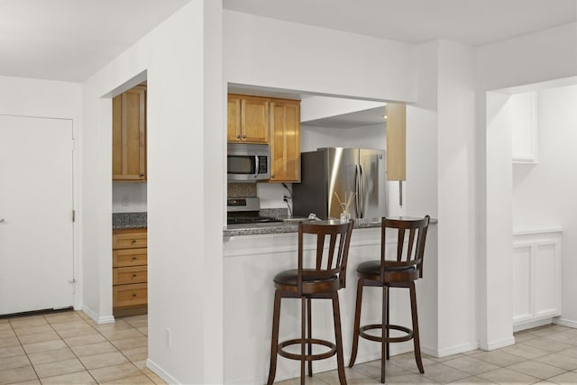 2171 Martinique Ln, Oxnard, CA 93035 - kitchen with stainless steel appliances, a kitchen breakfast bar, dark countertops, and light tile patterned floors