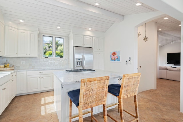 2641 Dorking Pl, Santa Barbara, CA 93105 - kitchen with stainless steel appliances, white cabinets, a kitchen bar, decorative backsplash, and arched walkways