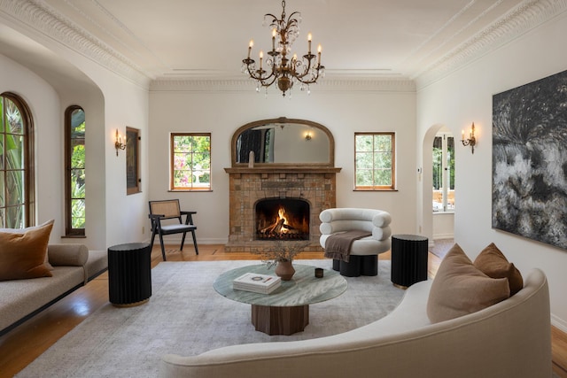 205 S Lomita Ave, Ojai, CA 93023 - living area with arched walkways, wood finished floors, a tiled fireplace, a chandelier, and crown molding