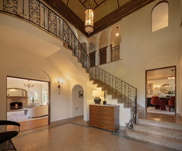 205 S Lomita Ave, Ojai, CA 93023 - stairs featuring a towering ceiling, arched walkways, inlaid floor details, a fireplace, and crown molding