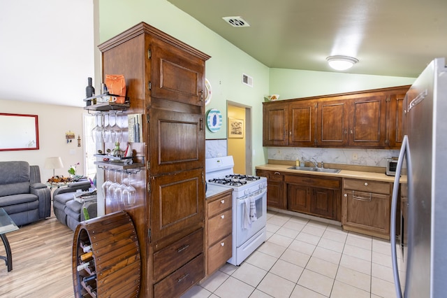 3608 Via Orilla, Lompoc, CA 93436 - kitchen featuring white gas range, freestanding refrigerator, vaulted ceiling, light countertops, and decorative backsplash
