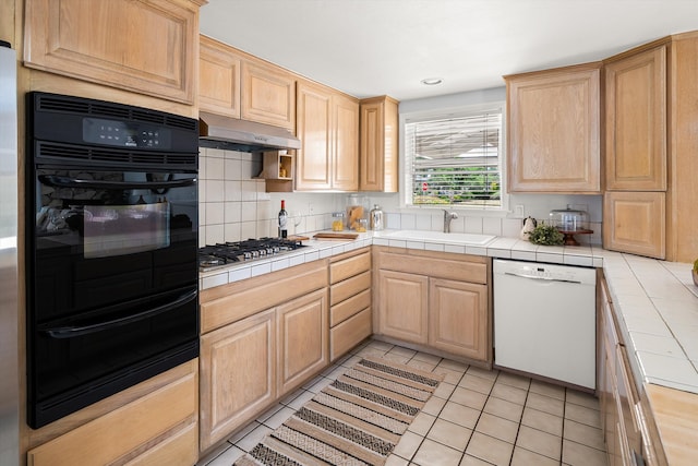 5668 Encina Rd, Goleta, CA 93117 - kitchen featuring dishwasher, a warming drawer, black oven, stainless steel gas cooktop, and under cabinet range hood