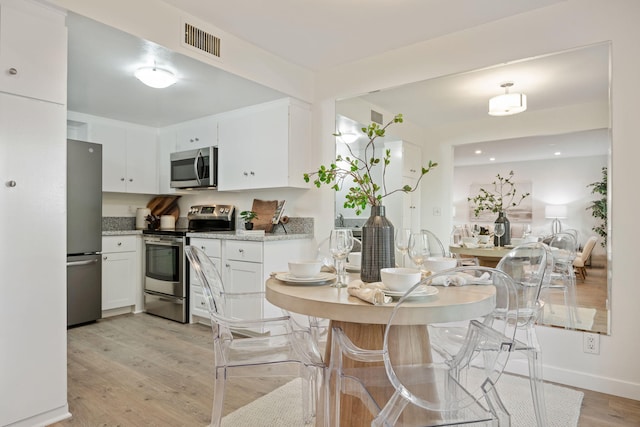 1701 Anacapa St Unit 6, Santa Barbara, CA 93101 - kitchen featuring stainless steel appliances, white cabinets, light wood-style floors, and light stone countertops
