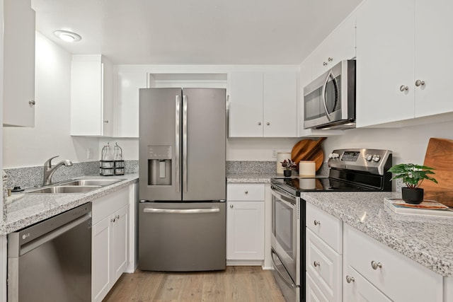 1701 Anacapa St Unit 6, Santa Barbara, CA 93101 - kitchen featuring appliances with stainless steel finishes, white cabinets, light wood finished floors, and light stone countertops