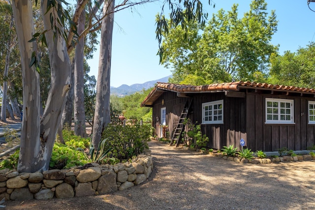 601 San Ysidro Rd, Santa Barbara, CA 93108 - view of front of home with board and batten siding, a mountain view, a tile roof, and an outdoor structure