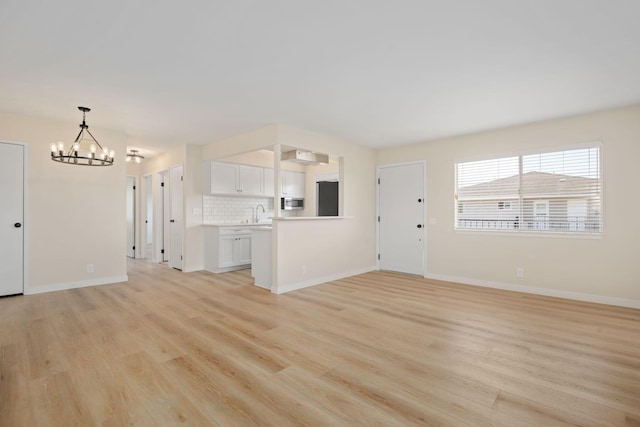 5925 Birch St Unit 4, Carpinteria, CA 93013 - unfurnished living room featuring a chandelier and light wood-type flooring