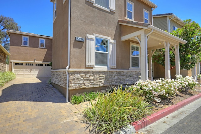 6628 Sand Castle Pl Unit C-7, Goleta, CA 93117 - view of front of property with stone siding, a garage, stucco siding, and decorative driveway
