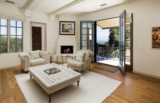 1439 Tunnel Rd, Santa Barbara, CA 93105 - living room with healthy amount of natural light, light wood-style floors, beamed ceiling, and a warm lit fireplace