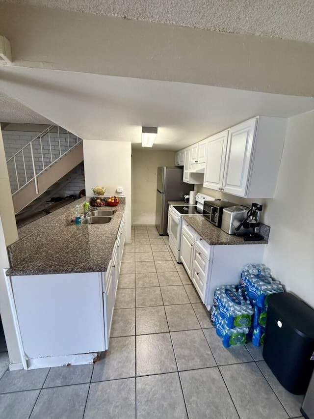 701 Halyard St, Port Hueneme, CA 93041 - kitchen with white electric range, white cabinets, light tile patterned floors, freestanding refrigerator, and dark stone counters
