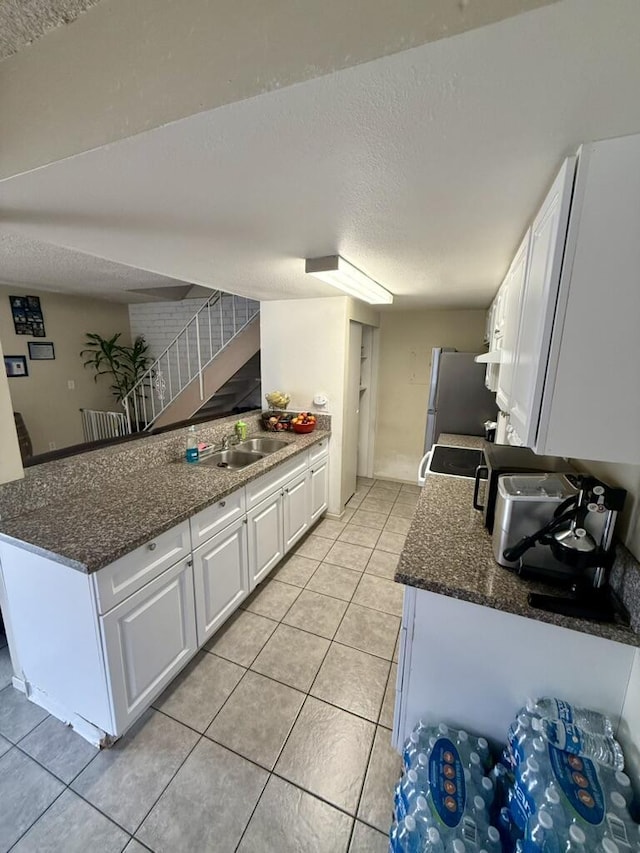 701 Halyard St, Port Hueneme, CA 93041 - kitchen featuring a textured ceiling, white cabinetry, light tile patterned flooring, dark stone countertops, and a peninsula