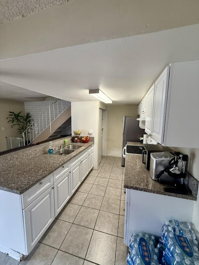 701 Halyard St, Port Hueneme, CA 93041 - kitchen featuring white cabinetry, a textured ceiling, light tile patterned floors, dark stone countertops, and a peninsula