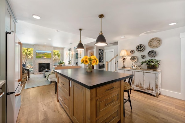 2807 Gaviota St, Los Olivos, CA 93441 - kitchen featuring dark countertops, white fridge, light wood-style flooring, a stone fireplace, and recessed lighting