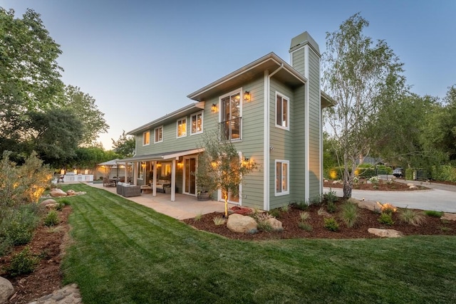 2807 Gaviota St, Los Olivos, CA 93441 - back of property at dusk with a chimney, a yard, a patio, and an outdoor living space