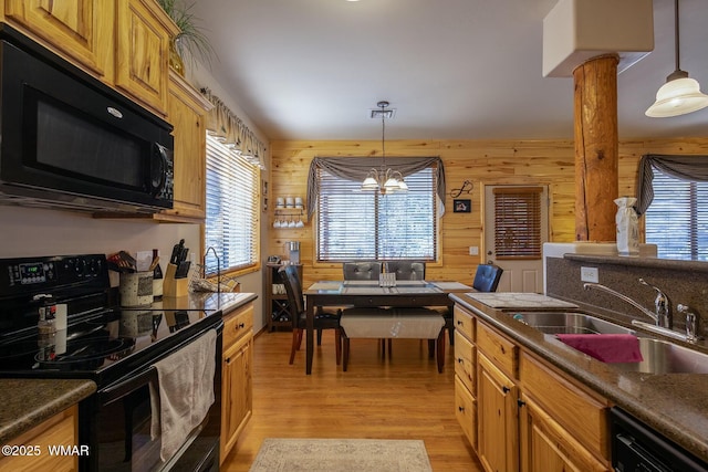 kitchen with dark countertops, decorative light fixtures, a sink, and black appliances