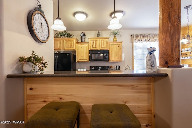 kitchen with dark countertops, decorative light fixtures, black appliances, and light brown cabinetry