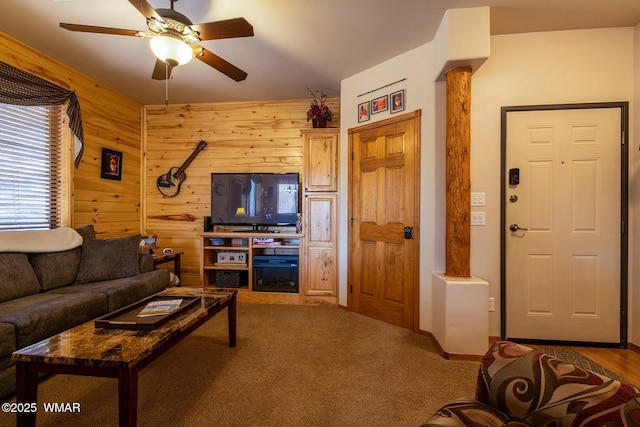 living room with carpet flooring, wood walls, ornate columns, and ceiling fan