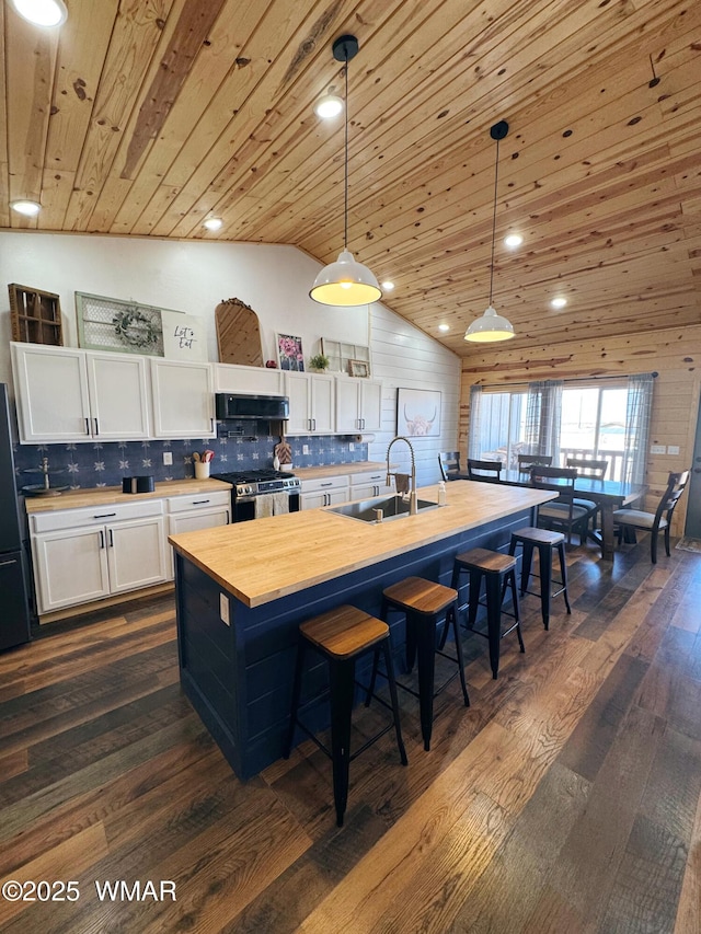 kitchen with hanging light fixtures, white cabinets, a sink, and exhaust hood