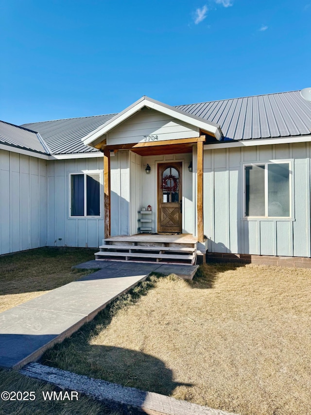 view of front facade featuring board and batten siding, metal roof, and a front lawn