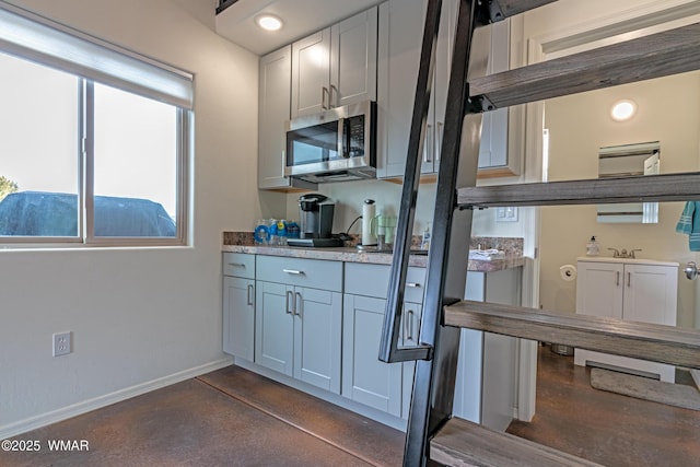 kitchen featuring stainless steel microwave, white cabinetry, and baseboards