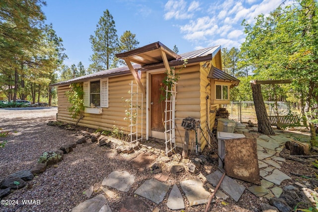 view of property exterior featuring fence and metal roof