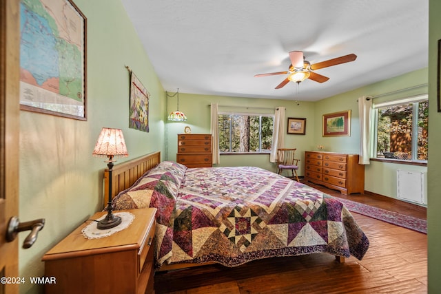 bedroom with multiple windows, wood finished floors, and a ceiling fan