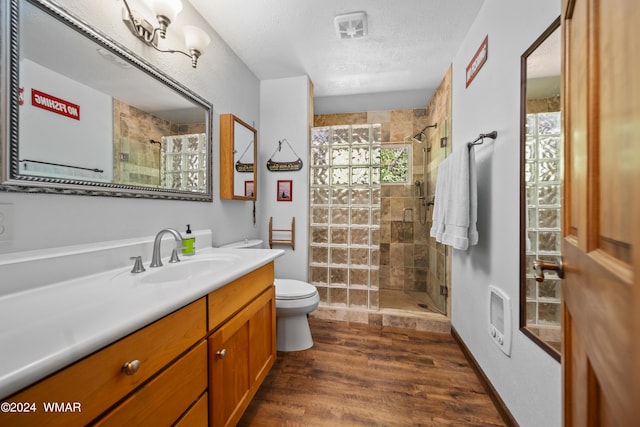 bathroom with toilet, wood finished floors, a textured ceiling, vanity, and a shower stall