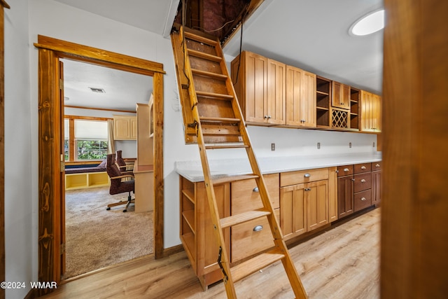 kitchen featuring visible vents, light colored carpet, light countertops, light wood-style floors, and open shelves