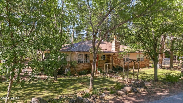 ranch-style house featuring stone siding, a chimney, and a front yard