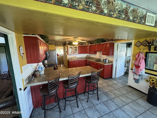7525 E E Sherwood Rd, Snowflake, AZ 85937 - kitchen with reddish brown cabinets, a peninsula, backsplash, tile patterned flooring, and ceiling fan