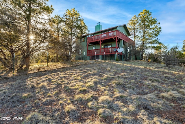 back of house featuring a chimney and a wooden deck