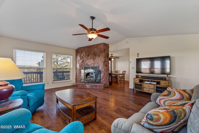 living room featuring ceiling fan, a stone fireplace, wood finished floors, baseboards, and lofted ceiling