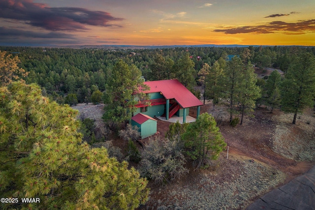 aerial view at dusk featuring a view of trees