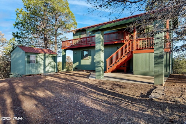 back of property with an outdoor structure, stairway, a shed, and a deck