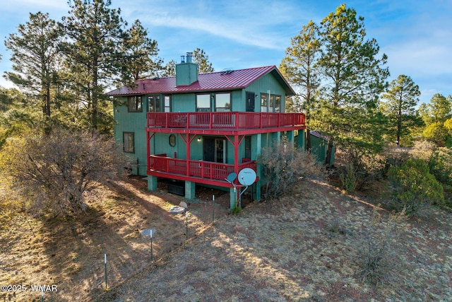 back of property featuring a deck, a chimney, and metal roof