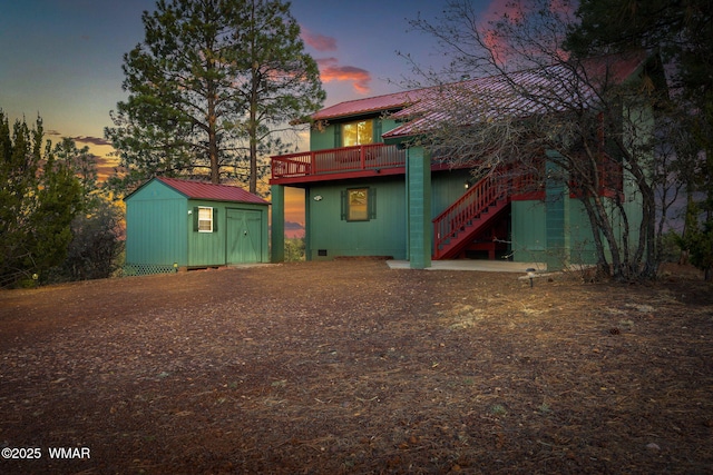 back of house with an outdoor structure, a deck, metal roof, a storage shed, and stairway