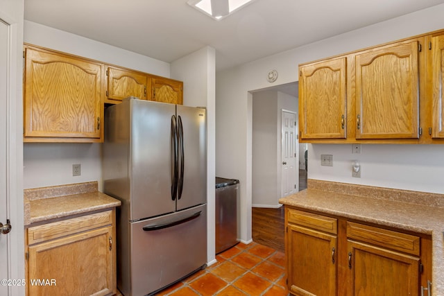 kitchen with dark tile patterned floors, freestanding refrigerator, washer / dryer, and light countertops