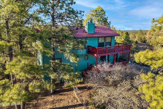 back of house with a chimney and a wooden deck