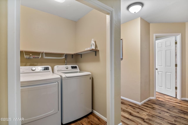 laundry room featuring laundry area, baseboards, washing machine and dryer, and wood finished floors