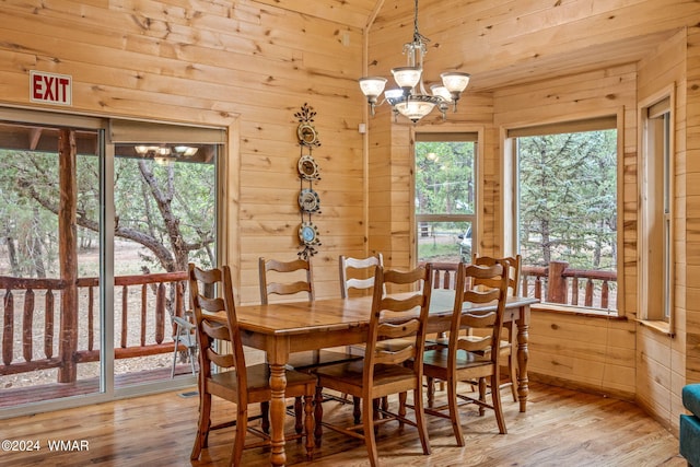 dining area with lofted ceiling, an inviting chandelier, wood finished floors, and wooden walls