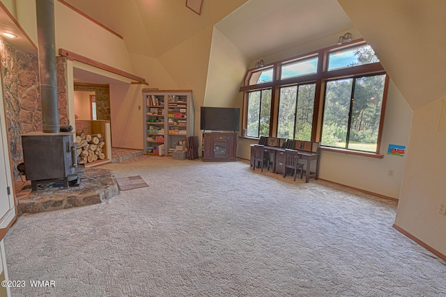 unfurnished living room with lofted ceiling, carpet flooring, a wood stove, and baseboards