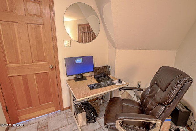 office space with stone tile floors and vaulted ceiling