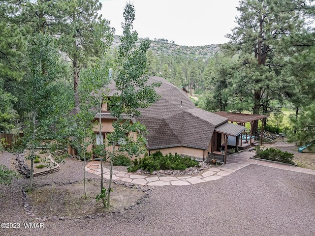 exterior space featuring a shingled roof and a patio