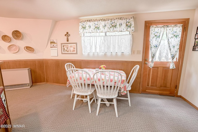 carpeted dining space with wainscoting and wooden walls
