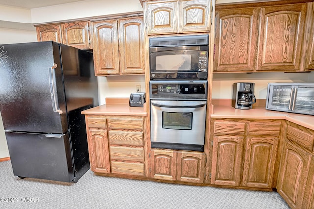 kitchen with brown cabinets, a toaster, light countertops, and black appliances