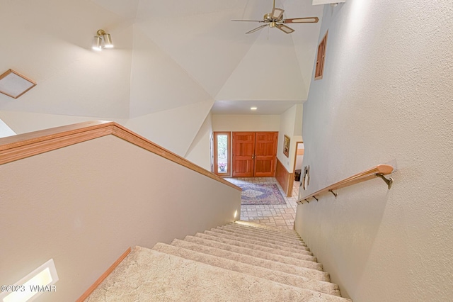 stairway featuring a high ceiling and a ceiling fan