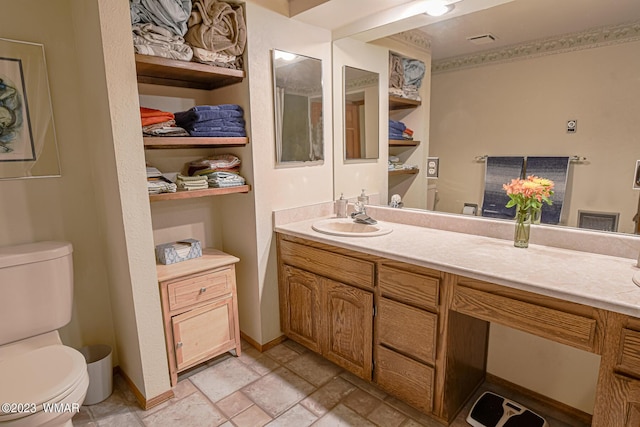 bathroom with stone tile floors, visible vents, toilet, vanity, and baseboards