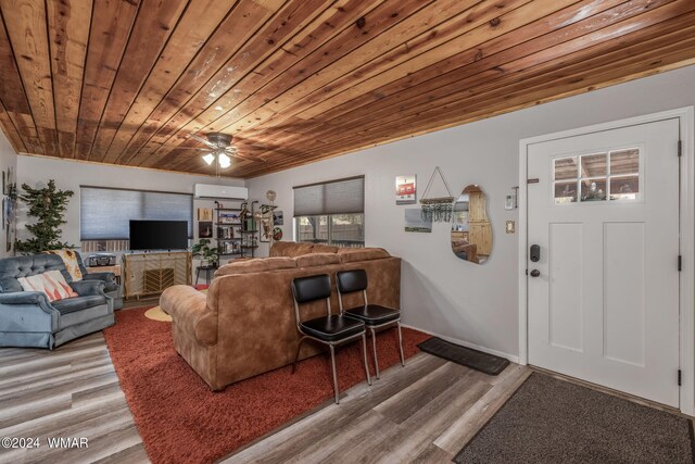 living area featuring a ceiling fan, wood ceiling, a wall unit AC, and wood finished floors