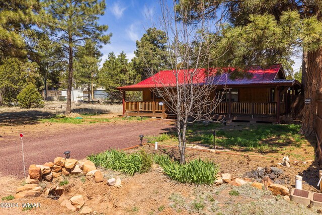 view of front of home featuring metal roof, a deck, and fence