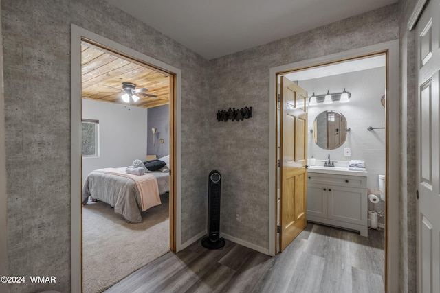 bathroom with wood finished floors, connected bathroom, vanity, and baseboards